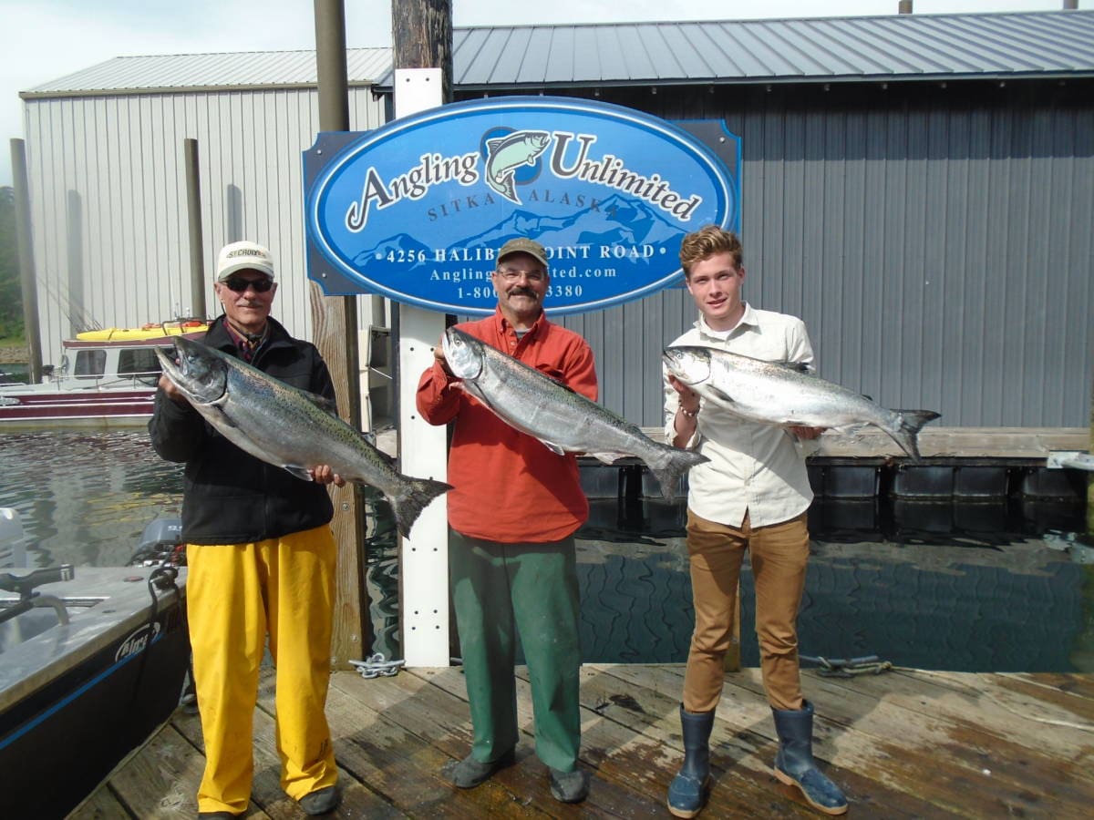 Angling Unlimited guests stand on the dock with salmon