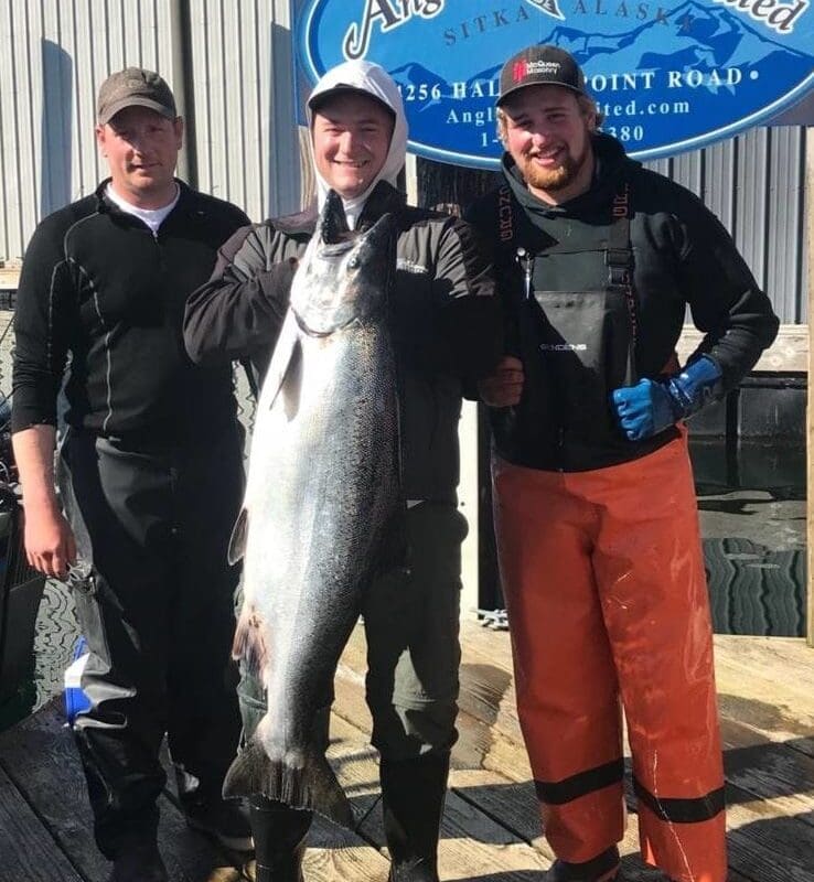 Men stand on the Angling Unlimited guest holding a salmon