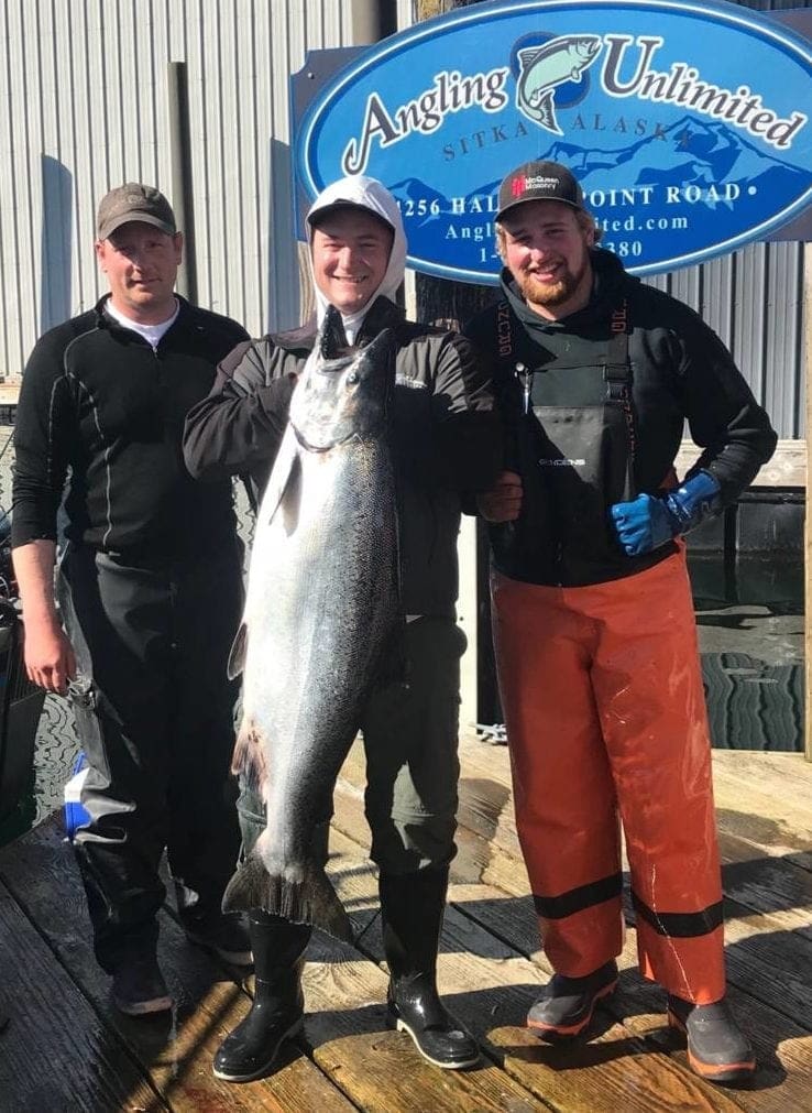 Men stand on the Angling Unlimited guest holding a salmon