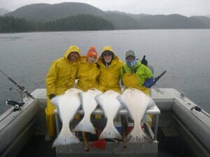 Brad & Reed Schoenfeld, Michael Hannan, Kevin Kumagai 4 people sitting behind 4 halibut on boat stern