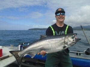 man in sunglasses holding large salmon caught fishing