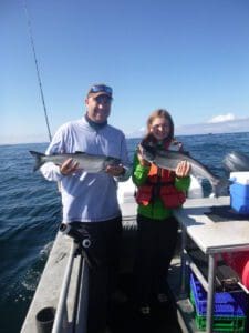 man and girl holding fish on boat while fishing