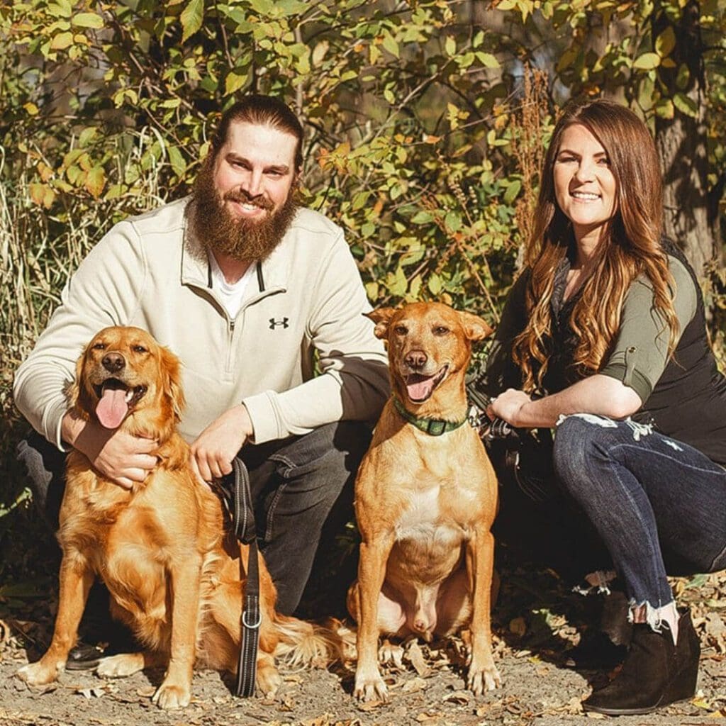 Couple sitting on the ground with two dogs
