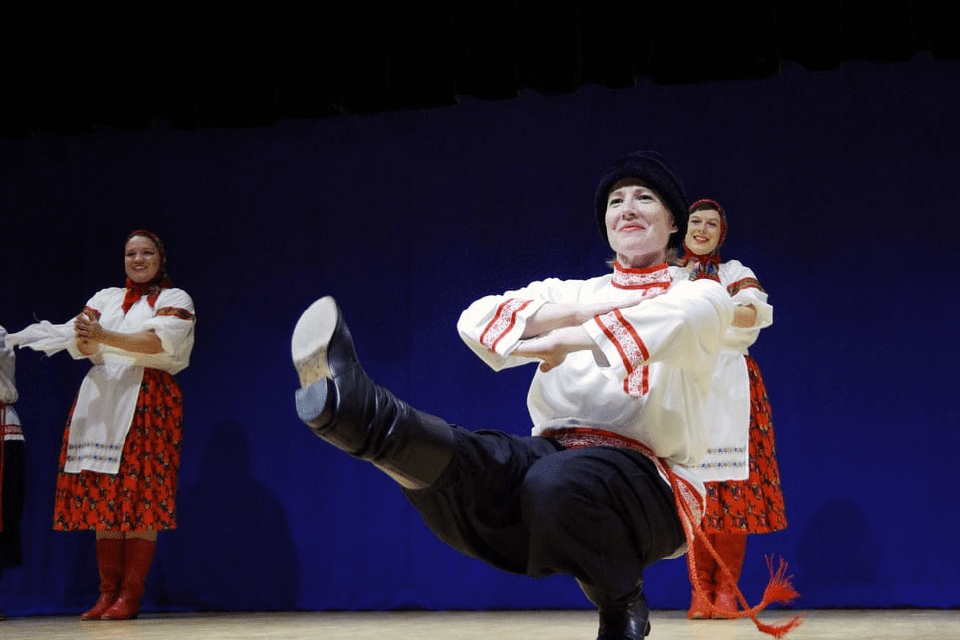 A woman dances with two women standing and clapping behind her