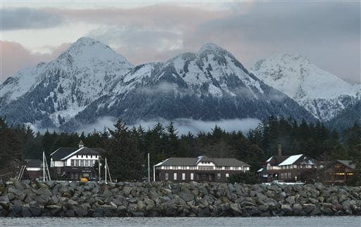Snow covered mountains stand tall behind low buildings in Sitka, Alaska