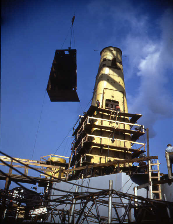 An overhead crane lowers a prefabricated structure onto IOWA for installation. Fall 1942 - 80-G-K-511 picture number 1