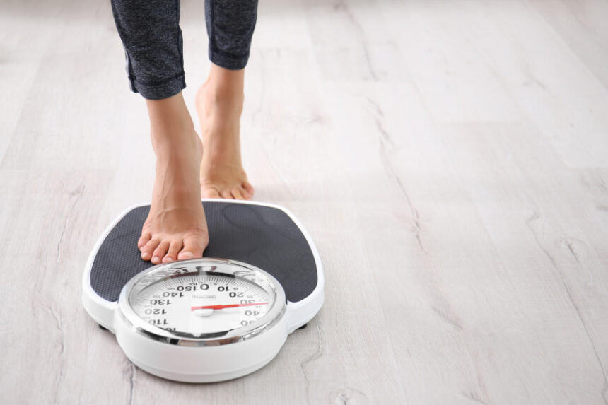Woman measuring her weight using scale