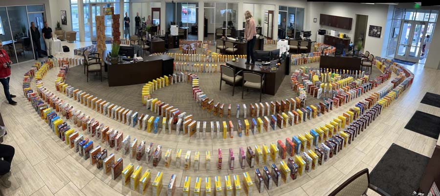 WATCH: Local bank creates huge line of dominoes out of donated cereal boxes for food pantry