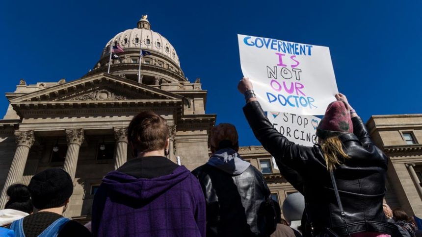 People gather in front of the Idaho Statehouse in opposition to anti-transgender legislation moving through an Idaho Republican congress, Friday, Feb. 24, 2023, in Boise, Idaho. The U.S. Supreme Court's decision on Monday, April 15, 2024, allows the state to put in place a 2023 law that subjects physicians to up to 10 years in prison if they provide hormones, puberty blockers or other gender-affirming care to people under age 18. A federal judge in Idaho had previously blocked the law in its entirety. (Darin Oswald/Idaho Statesman via AP, File)
