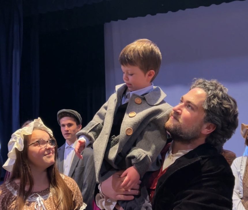 Man in costume carrying a boy on stage