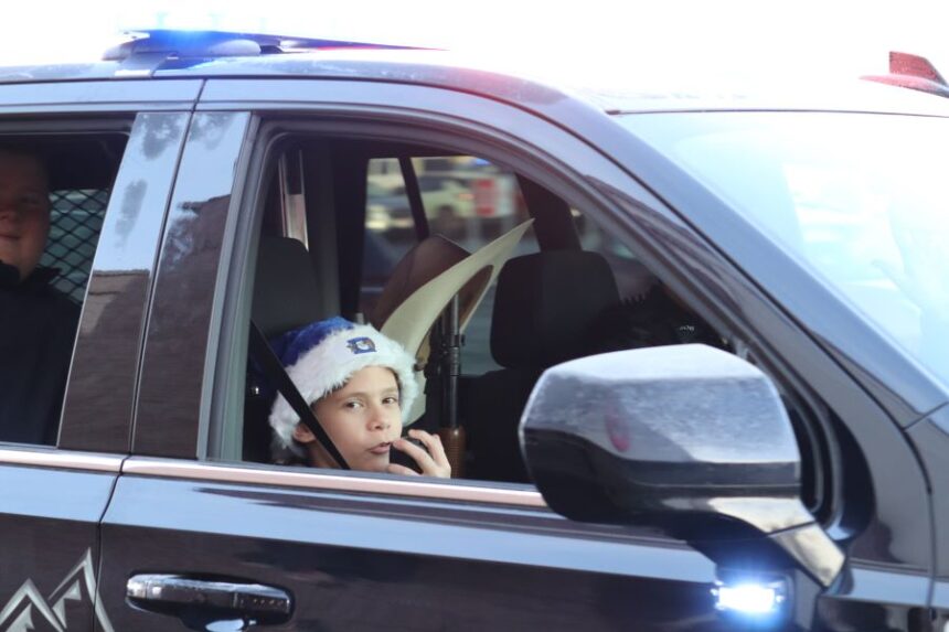 A Shop with a Cop recipient playing with a police radio during the parade. | Jessica Clements, Idaho Falls Police Department