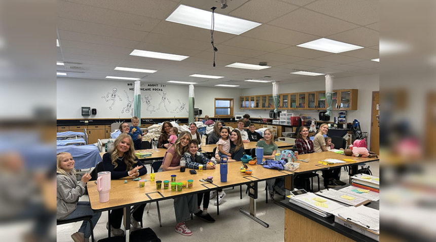 Snake River High School's CNA class, which consists mostly of seniors, smile for a picture with their kid they brought to school for their senior prank.