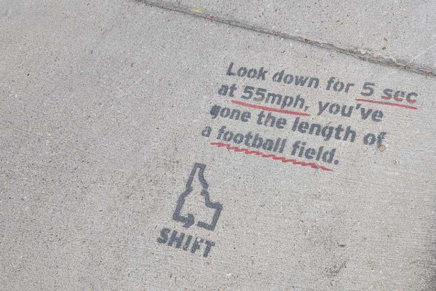 Text on a sidewalk in downtown Boise reminding drivers to pay attention: "Look down for 5 sec at 55 mph, you've gone the length of a football field."