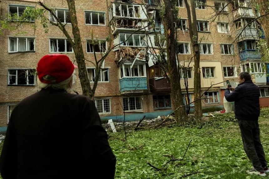 Residents look at an apartment building in Kyiv, Ukraine, that was damaged during a Russian attack, on Saturday. Thomas Peter/Reuters