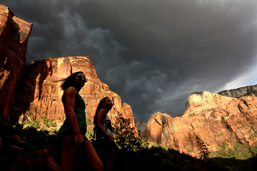 FILE - Hikers look up at a fast moving storm as it makes its way through Zion National Park outside of Springdale, Utah, July 22, 2013. (AP Photo/Sandy Huffaker, File)
