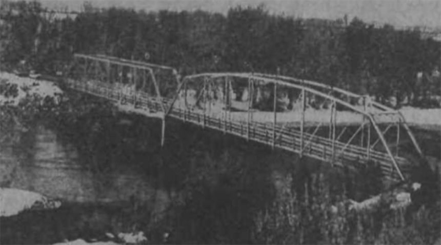 It replaced the Nelson and later the Holt Ferry as the southern crossing to get to Heise Hot Springs. The Bertha Gavin Bridge was built in 1938 and dedicated the fall of that year to honor Mrs. Gavin and her father, Richard Heise, who founded the springs. The bridge will be replaced by a new structure, but the memory of the ferries which served the resort trade and its first bridge, will be among the momentoes which local history will save. The double span bridge across the South Fork is not all of steel construction. A wider bridge will replace it. Caption dated May 29, 1975.