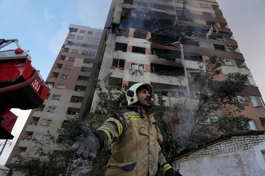 A firefighter calls out his colleagues at the scene of an explosion in a residence compound in northern Tehran, Iran, Friday, June 13, 2025. | Vahid Salemi, Associated Press
