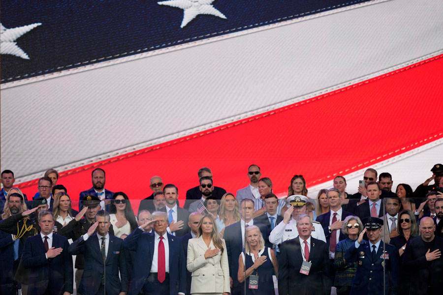 President Donald Trump, first lady Melania Trump, and other guests stand for the National Anthem, during a military parade commemorating the Army's 250th anniversary, coinciding with his 79th birthday, Saturday, June 14, 2025, in Washington. (AP Photo/Julia Demaree Nikhinson)