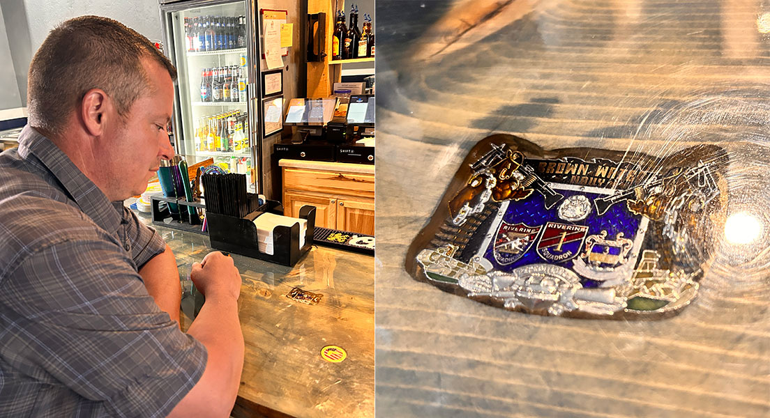 Mark McClure, left, looking at a military coin on display in the bar of his new business. It's a chief's mess coin he acquired from his commanding officer in the 2010s. | Rett Nelson, EastIdahoNews.com
