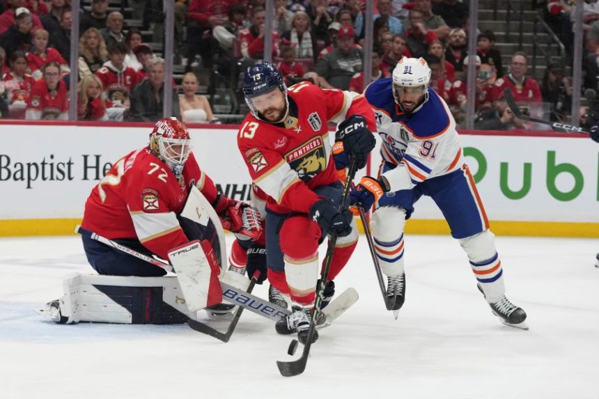 Florida Panthers center Sam Reinhart (13) hits a shot by Edmonton Oilers left wing Evander Kane (91) away from the goal during the third period of Game 3 of the NHL Stanley Cup final Monday, June 9, 2025, in Sunrise, Fla. (AP Photo/Lynne Sladky)