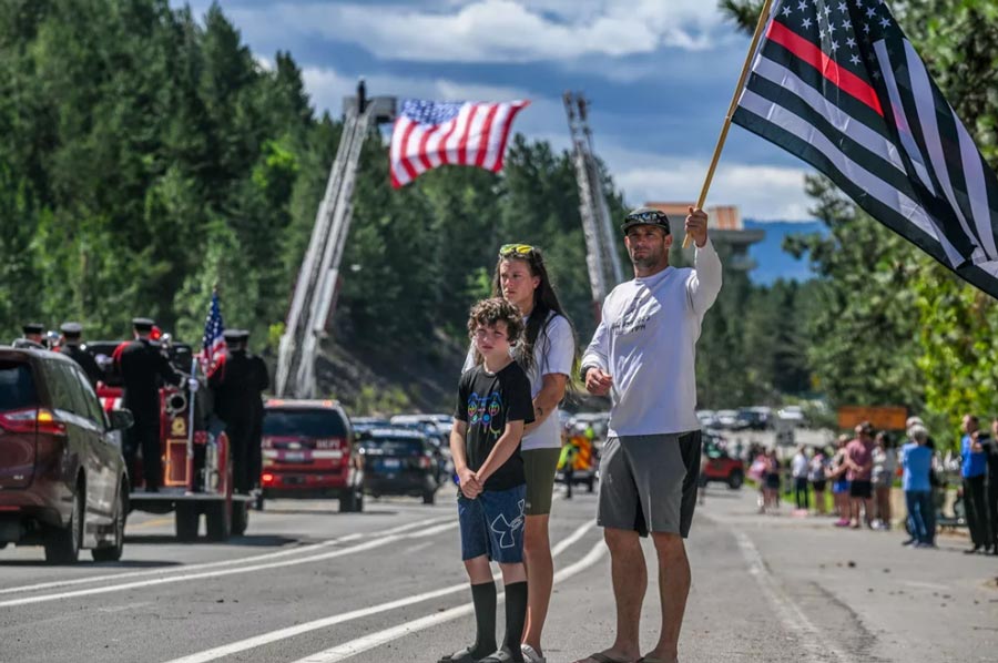 We’re good friends of Frank and paying respect for John,” Will Andrews said while standing with his wife Kenzie and son Waylon, 9, on Thursday during the funeral procession for Battalion Chief John Morrison in Coeur d’Alene. Kootenai Fire & Rescue Battalion Chief Frank Harwood’s funeral is on Friday. | Kathy Plonka, The Spokesman-Review