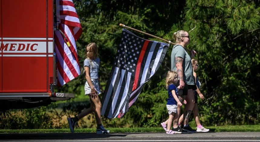 “Our community comes together,” says Erin Stemmermann as she walks with her children Katie, 2, Emily, 8, and Hailey, 9, during the funeral procession Friday for Kootenai Fire & Rescue Battalion Chief Frank Harwood in Coeur d’Alene. | Kathy Plonka, The Spokesman-Review