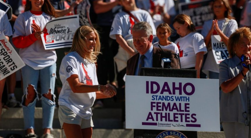 Riley Gaines, a former collegiate swimmer and national figure in the transgender athletics debate, shakes hands with Idaho Gov. Brad Little in August, after the Republican governor announced an executive order defending “fairness in women’s sports.” | Idaho EdNews photo