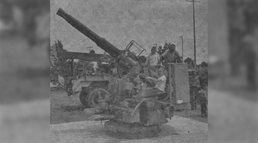 "Gun crews" were on hand by the dozen when the 40mm, anti-aircraft machine guns were installed on their concrete bases last Friday afternoon. They are urged by the Veterans of Foreign Wars, who secured the guns from the Naval Ordnance at Pocatello, to take pride in the memorial pieces and refrain from removing parts from them. The above gun is placed at Rigby City Park. A like memorial was placed at Ririe City Park. Caption dated July 2, 1959.
