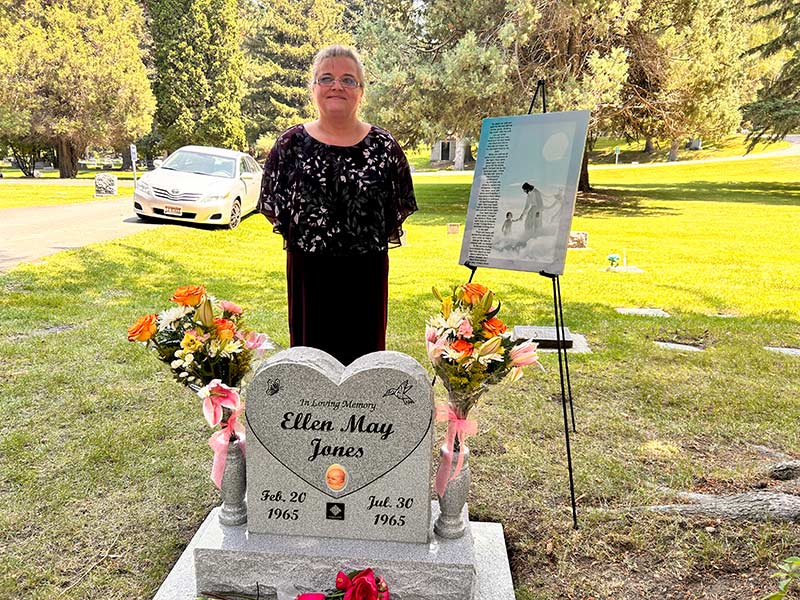 Charlene Goetz next to her sister's headstone at Rose Hill Cemetery. | Rett Nelson, EastIdahoNews.com