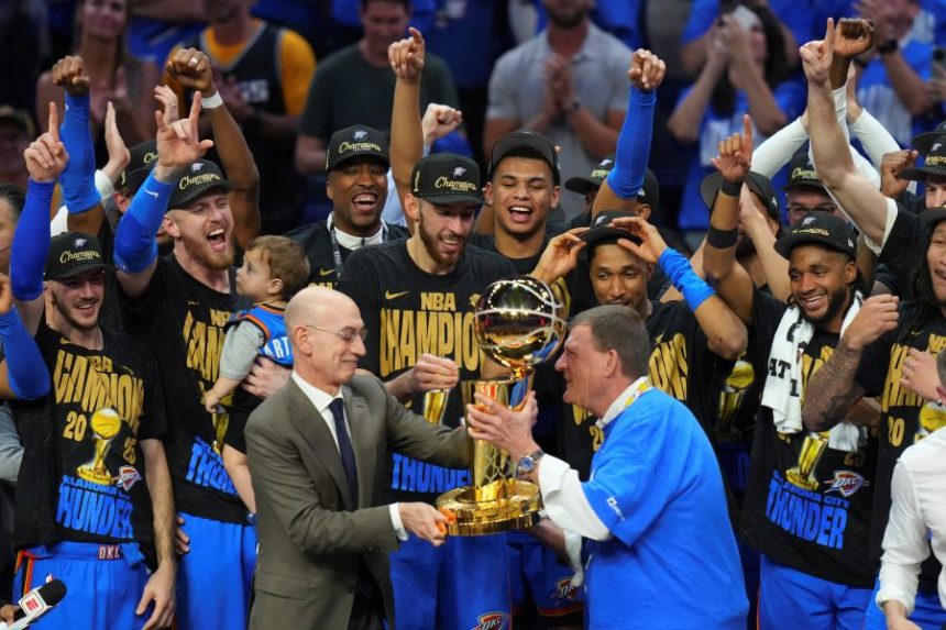Clay Bennett, center right, chairman the ownership group of the Oklahoma City Thunder, receives the Larry O'Brien Championship Trophy from NBA Commissioner Adam Silver, center left, after winning the NBA basketball championship with a Game 7 victory against the Indiana Pacers Sunday, June 22, 2025, in Oklahoma City. (AP Photo/Nate Billings)