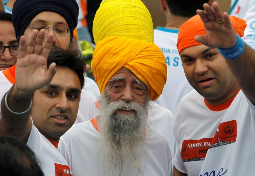 FILE - Centenarian marathon runner Fauja Singh, center, smiles after finishing a 10-kilometer race, held as part of the annual Hong Kong Marathon, in Hong Kong, Feb. 24, 2013. (AP Photo/Vincent Yu, file)