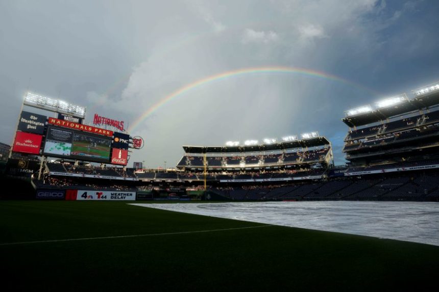 A rainbow forms while a tarp is on the field as the start of a baseball game between the Washington Nationals and the Colorado Rockies is delayed due to weather at Nationals Park, Wednesday, June 18, 2025, in Washington. (AP Photo/Jess Rapfogel)