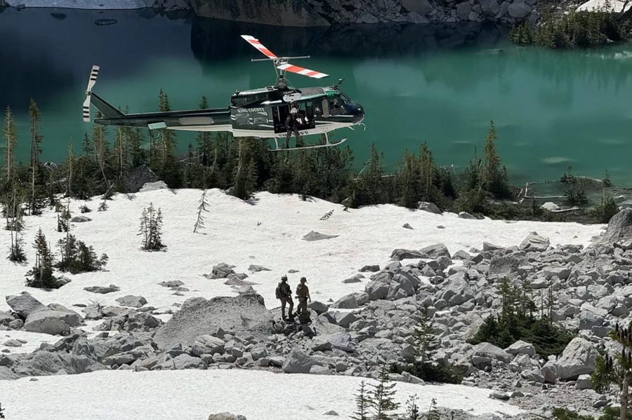 A King County Sheriff’s Office helicopter flies over two U.S. Marshals during the search for Travis Decker in June.