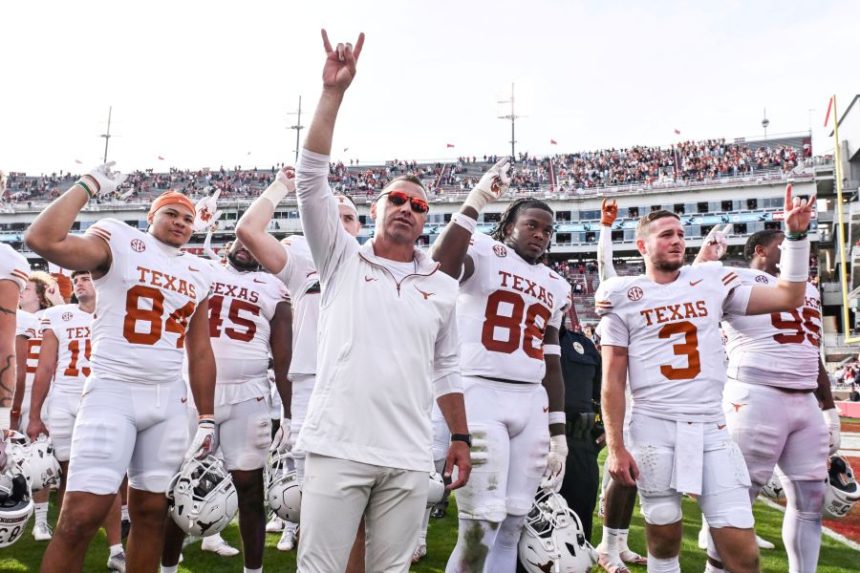FILE - Texas tight end Jordan Washington (84), coach Steve Sarkisian, defensive back Barryn Sorrell (88) and quarterback Quinn Ewers (3) celebrate with their team after defeating Arkansas in an NCAA college football game Saturday, Nov. 16, 2024, in Fayetteville, Ark. (AP Photo/Michael Woods, File)