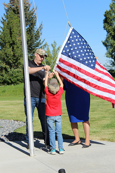 The Byers family raising the American flag in front of their new home. | Kaitlyn Hart, EastIdahoNews.com | Kaitlyn Hart, EastIdahoNews.com.