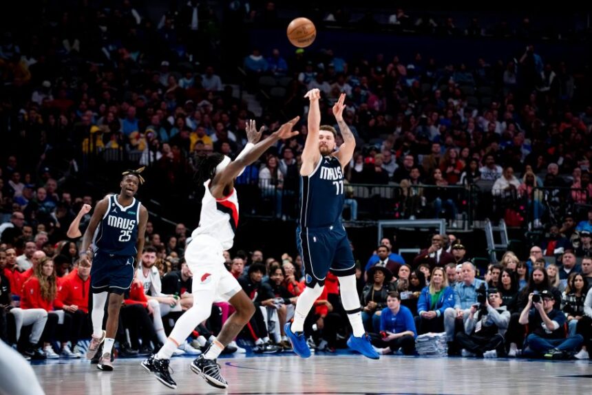 FILE - Dallas Mavericks guard Luka Doncic (77) heaves a shot from half court over Portland Trail Blazers forward Jerami Grant (9) as the buzzer sounds in the first half of an NBA basketball game in Dallas, Dec. 16, 2022. (AP Photo/Emil Lippe, File)