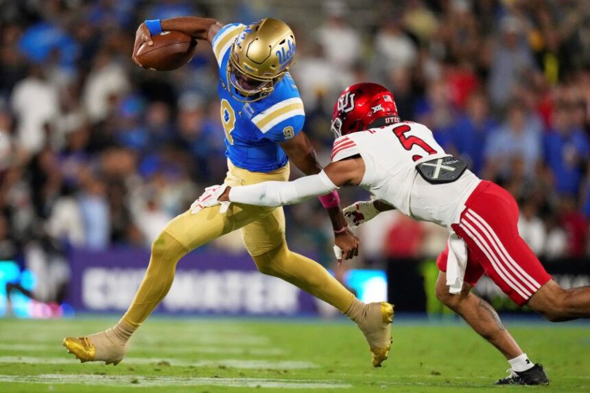 UCLA quarterback Nico Iamaleava, left, avoids a tackle by Utah safety Tao Johnson during the first half of an NCAA college football game, Saturday, Aug. 30, 2025, in Pasadena, Calif. (AP Photo/Mark J. Terrill)
