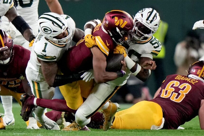Washington Commanders quarterback Jayden Daniels is sacked by Green Bay Packers linebacker Edgerrin Cooper, right, and defensive lineman Micah Parsons (1) during the second half of an NFL football game Thursday, Sept. 11, 2025, in Green Bay, Wis. (AP Photo/Morry Gash)