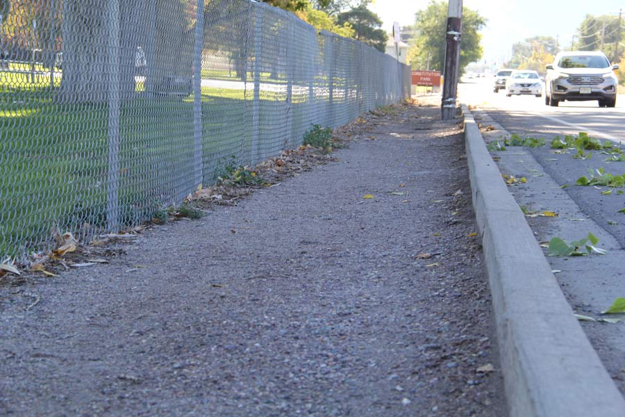 Gravel in place of where a sidewalk could be leading up to Centennial Park.