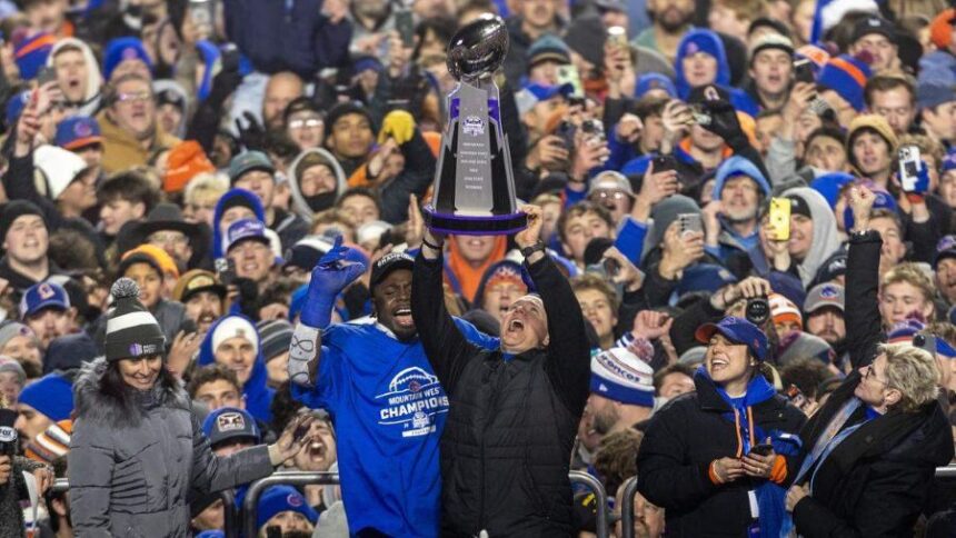 Boise State head coach Spencer Danielson holds up the Mountain West championship trophy with former Bronco safety Seyi Oladipo at his side after defeating UNLV 21-7 at Albertsons Stadium in December 2024. Darin Oswald doswald@idahostatesman.com