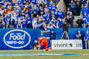 BYU quarterback Bear Bachmeier leaps over Utah’s Jackson Bennee during Saturday’s game against Utah at LaVell Edwards Stadium. | Tyler Staten for KSL.com.