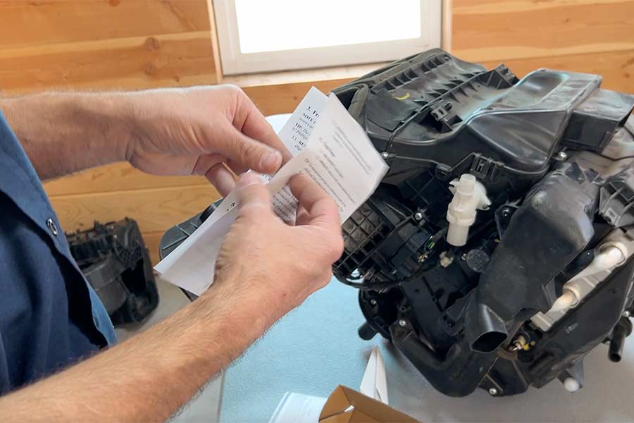 Nathan Hansen looks at instructions inside his kit showing people how to repair a mechanism on the AC/heater block for a Nissan Rogue. | Rett Nelson, EastIdahoNews.com
