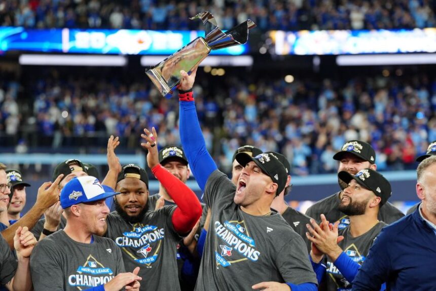 Toronto Blue Jays' George Springer holds the American League Championship Series trophy as the team celebrates after defeating the Seattle Mariners in Game 7 of the series in Toronto, Monday, Oct. 20, 2025. (Frank Gunn/The Canadian Press via AP)