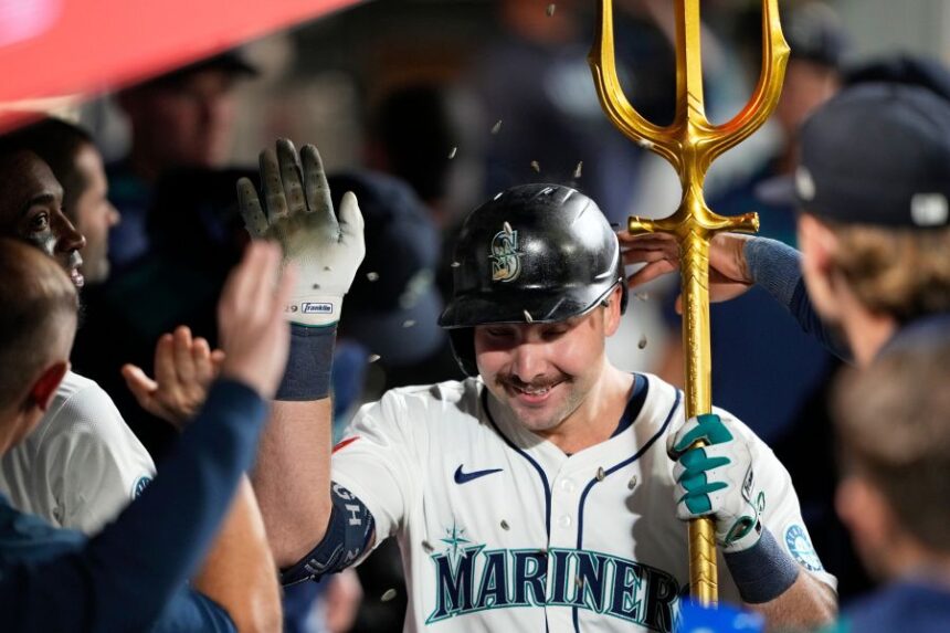 Seattle Mariners' Cal Raleigh celebrates in the dugout after hitting his 60th home run during the eighth inning of a baseball game against the Colorado Rockies, Wednesday, Sept. 24, 2025, in Seattle. (AP Photo/Ryan Sun)