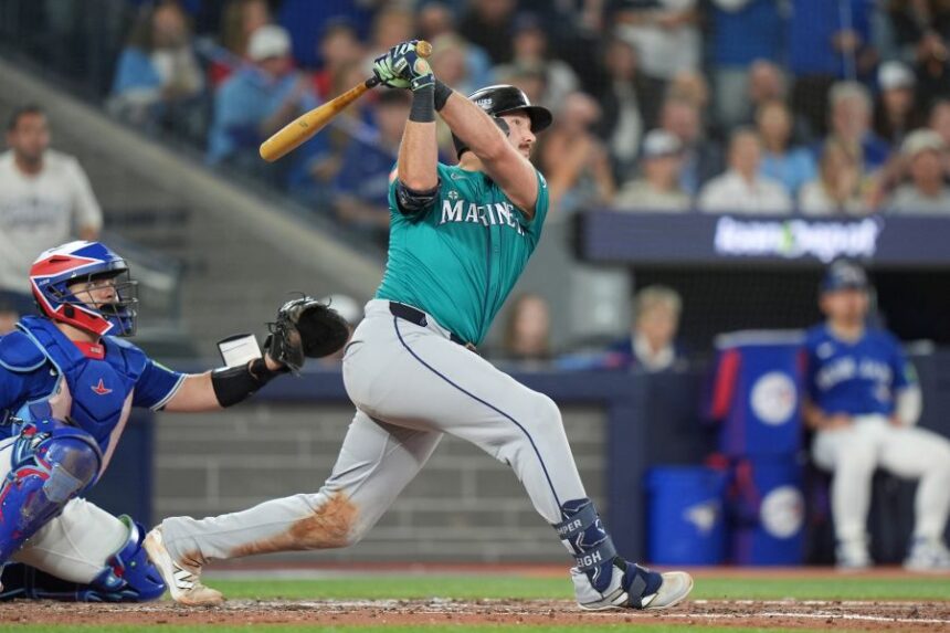 Seattle Mariners' Cal Raleigh (29) hits a home run in front of Toronto Blue Jays catcher Alejandro Kirk (30) sixth inning American League Championship Series baseball action in Toronto on Sunday, Oct. 12, 2025. (Frank Gunn/The Canadian Press via AP)