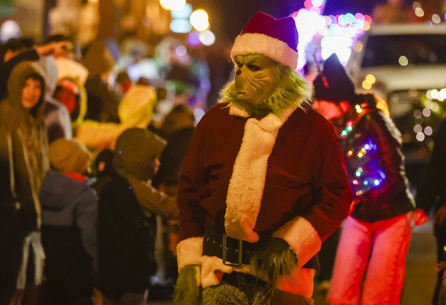 The Grinch marches down the route during the 2025 Christmas Lights Parade, drawing cheers from bundled-up spectators lining the street.  
