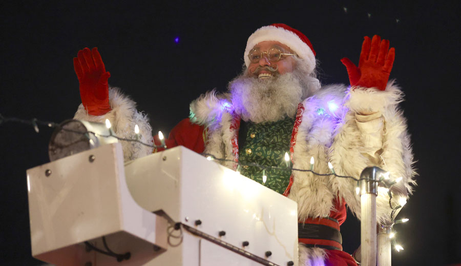 Santa waves to spectators from atop a decorated fire truck during the 2025 Christmas Night Lights Parade, exciting crowds as he rolls through.   