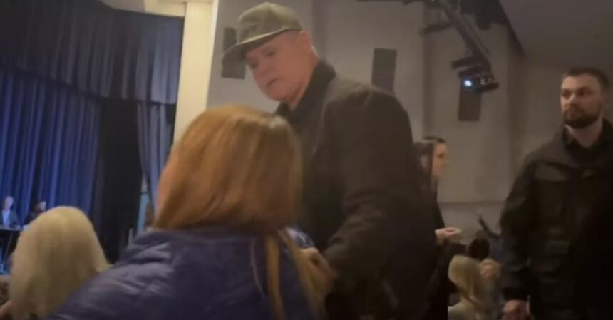 This screenshot from a video recording shows Kootenai County Sheriff Bob Norris grabbing the arm of Teresa Borrenpohl during a town hall meeting in February.