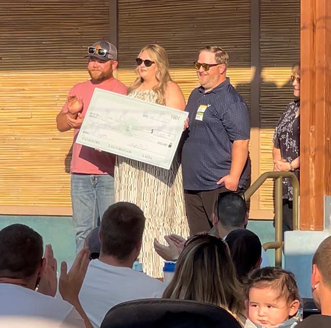 Brandon Hurst, left, presenting a check to a couple from money he raised at his pumpkin patch. | Courtesy Brandon Hurst