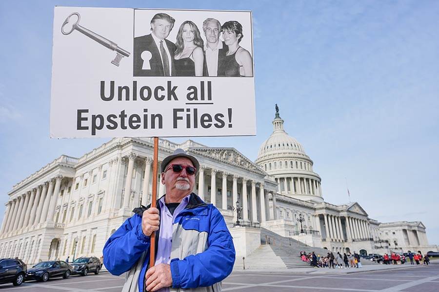 man holds sign calling for release of Epstein files